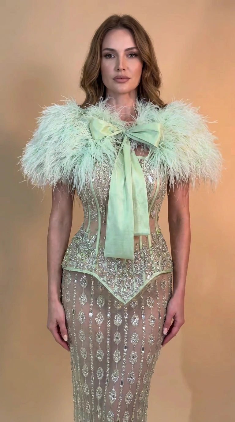 Front view of model wearing Mint Green feather trim sequin corset evening gown with front bow
