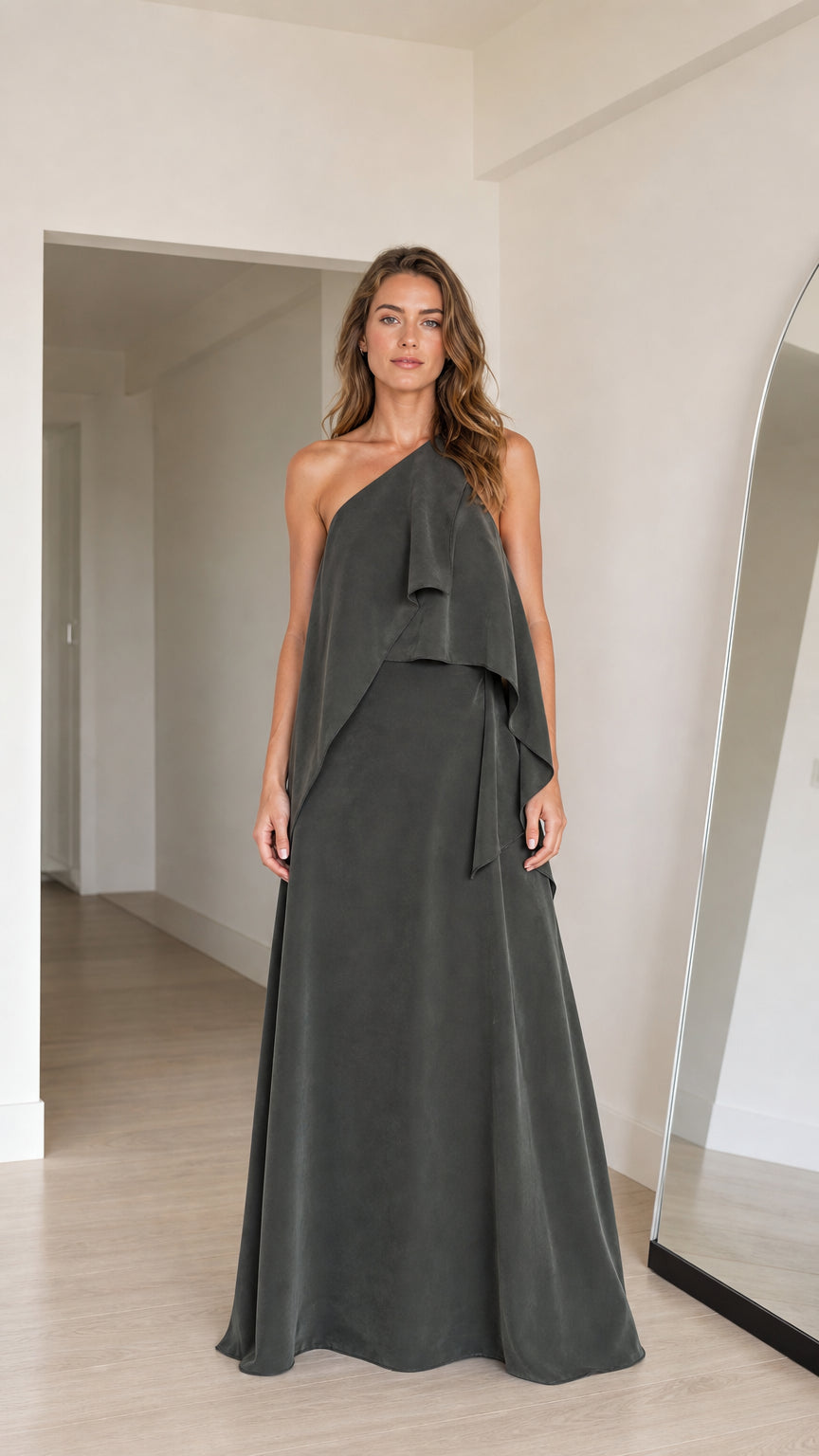 Front view of model wearing charcoal grey one-shoulder tiered draped maxi dress