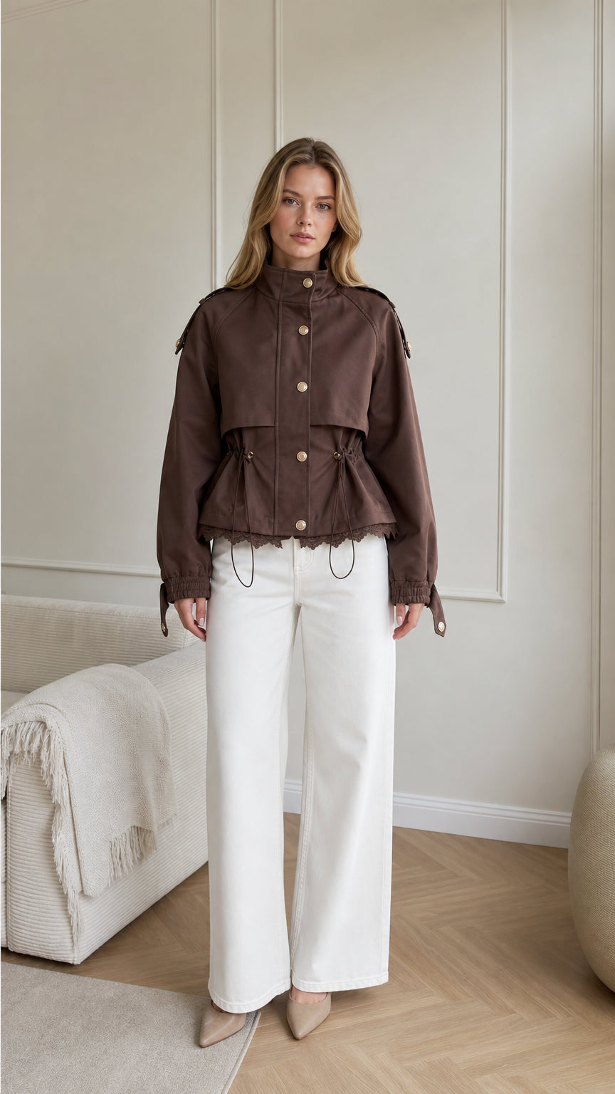 Front view of woman wearing brown cropped utility jacket with lace trim and white wide-leg trousers
