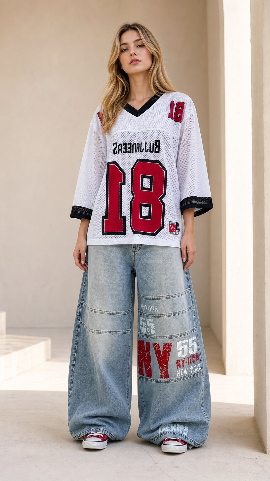 Front full view of woman wearing white oversized mesh graphic football jersey with wide-leg jeans