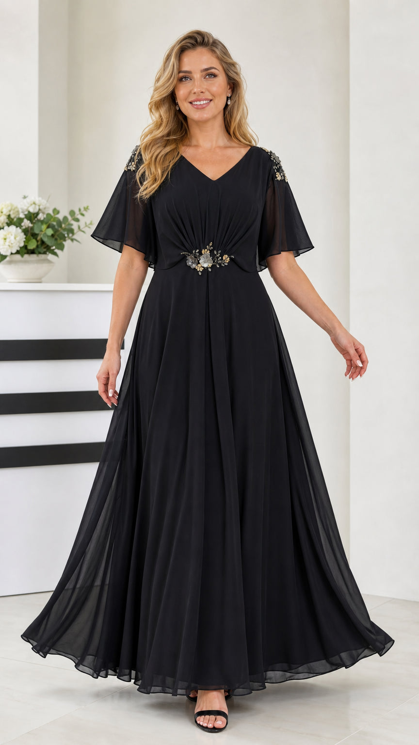 Front view of black flutter sleeve chiffon maxi evening dress with beaded waist detail