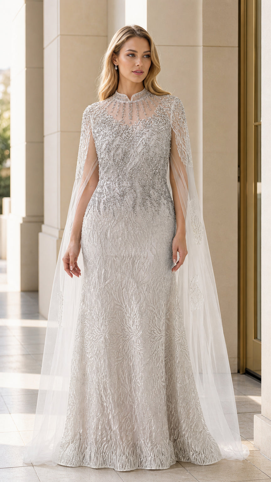 Front view of model wearing silver beaded evening gown with sheer cape overlay