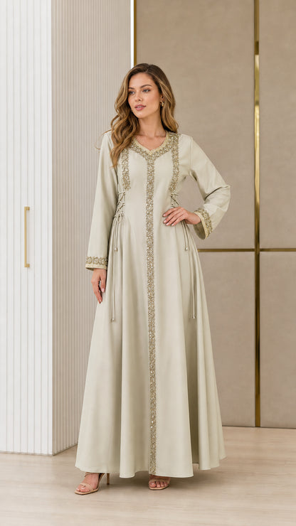 Model wearing sage green embroidered kaftan maxi dress with lace-up waist detail front view