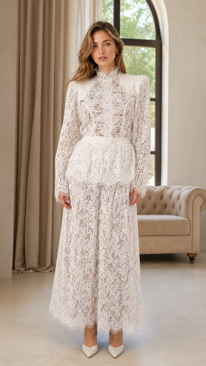 Front full view of woman wearing white floral lace mock neck wide leg jumpsuit with peplum