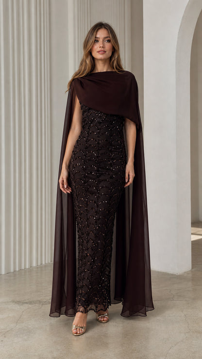 Front view of model wearing dark brown sequin column maxi dress with flowing chiffon cape