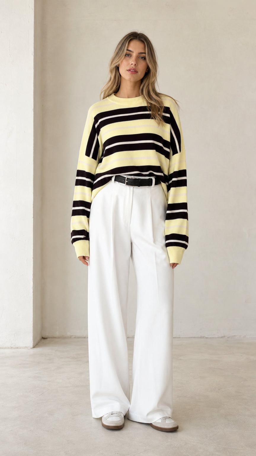 Front view of woman wearing pale yellow striped crewneck knit sweater with white wide-leg trousers