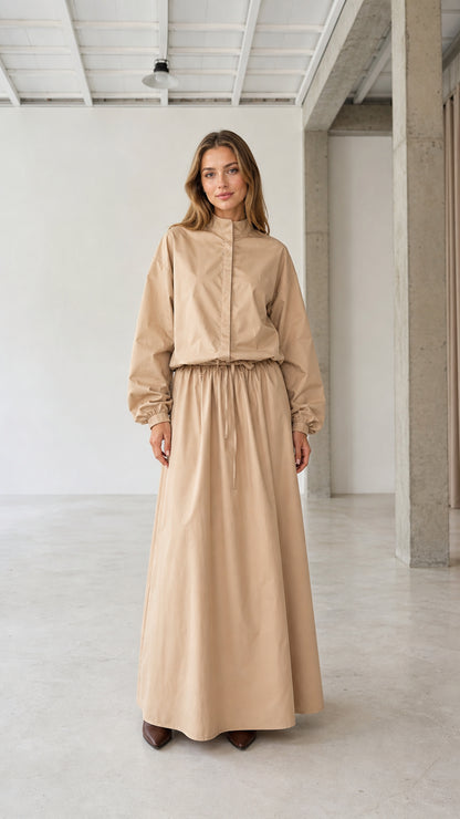 Front full view of woman wearing beige stand collar long sleeve drawstring maxi dress