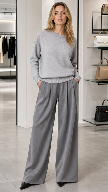 Front view of model wearing a light grey relaxed crewneck knit sweater with wide-leg grey trousers