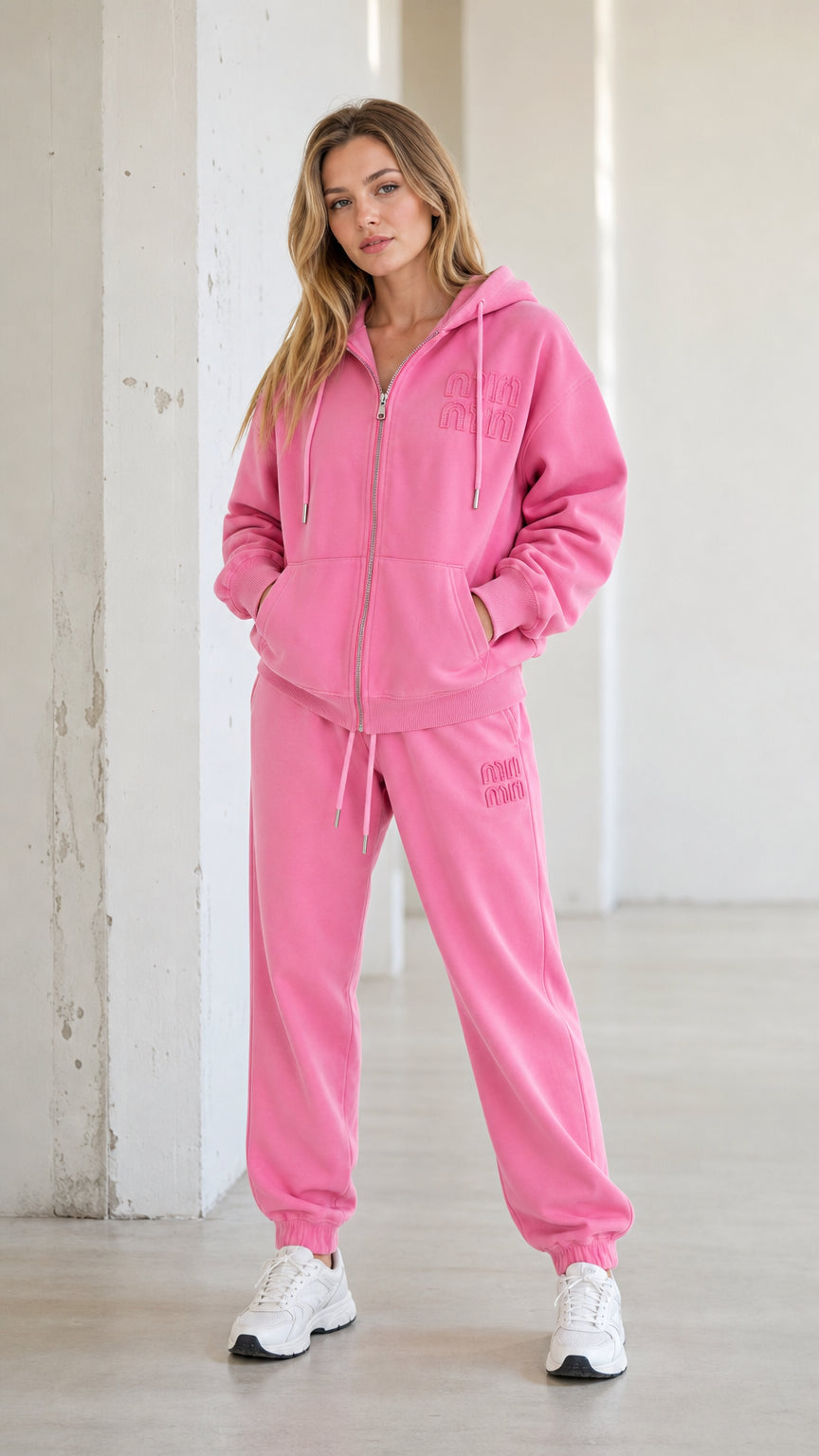 Front full-body view of model wearing pink full-zip hoodie and matching jogger set with white sneakers