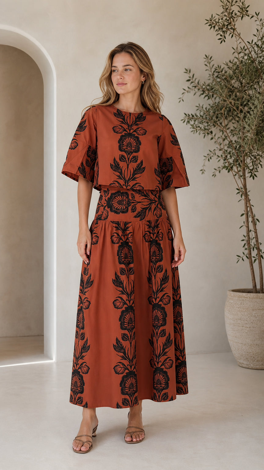 Front view of woman wearing rust floral print crop top and matching maxi skirt set