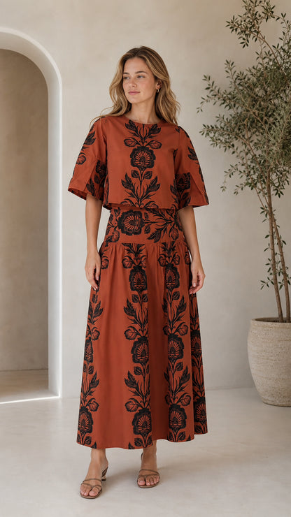 Front view of woman wearing rust floral print crop top and matching maxi skirt set