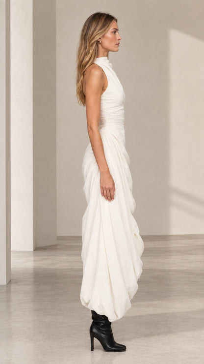 Side profile of model in ivory sleeveless draped maxi dress with bubble hem