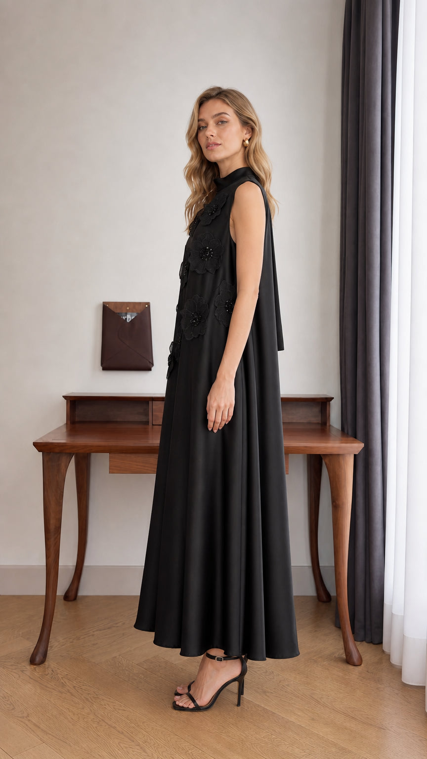 Side view of model in Black sleeveless flowing trapeze maxi dress