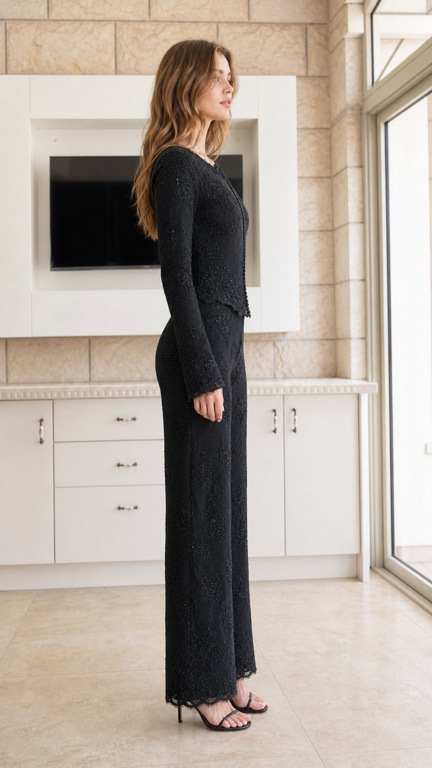 Side profile view of woman wearing black long-sleeve lace top and matching wide-leg pants