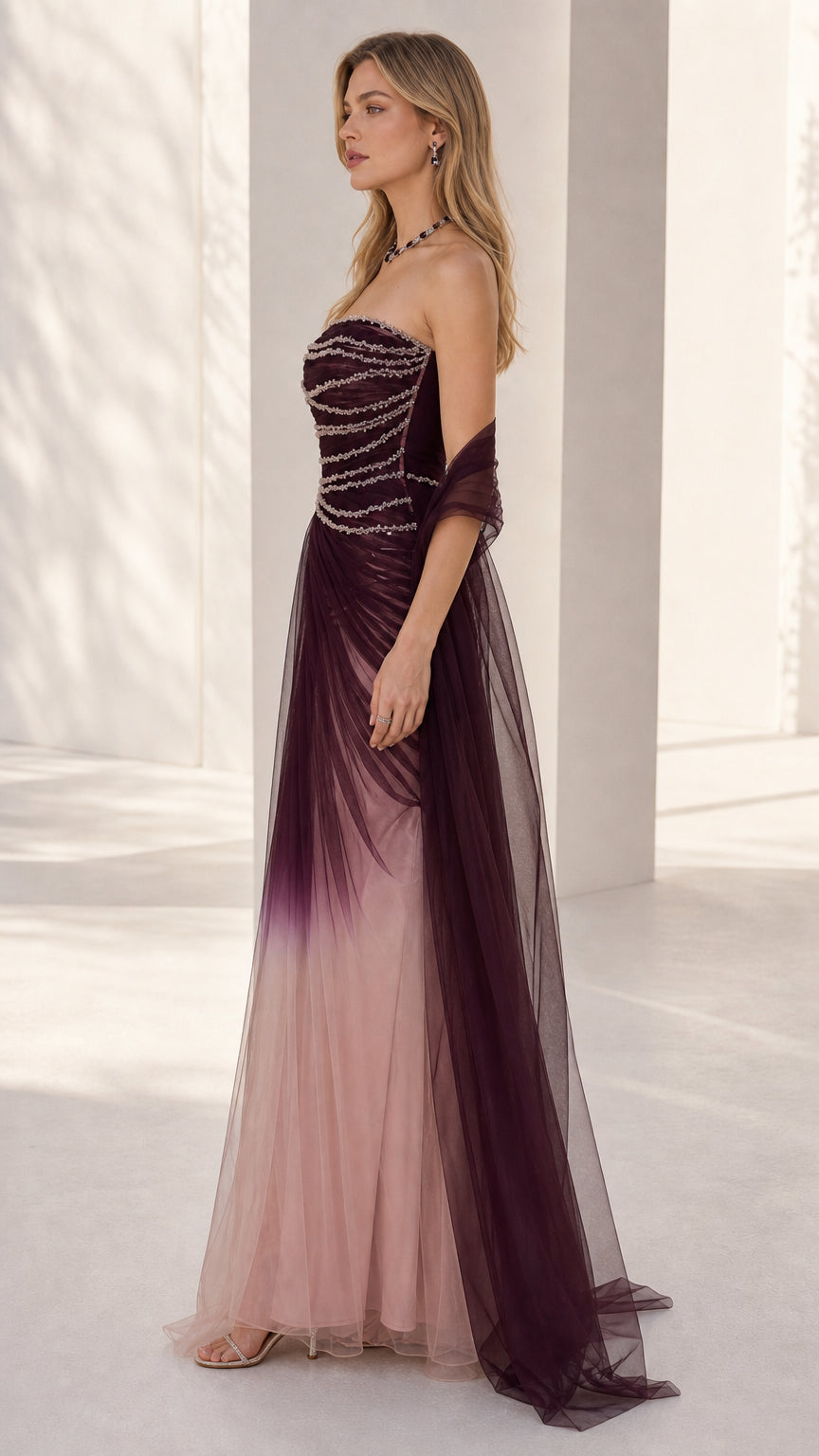 Side profile of the burgundy ombre strapless tulle gown showing fitted beaded bodice and skirt drape