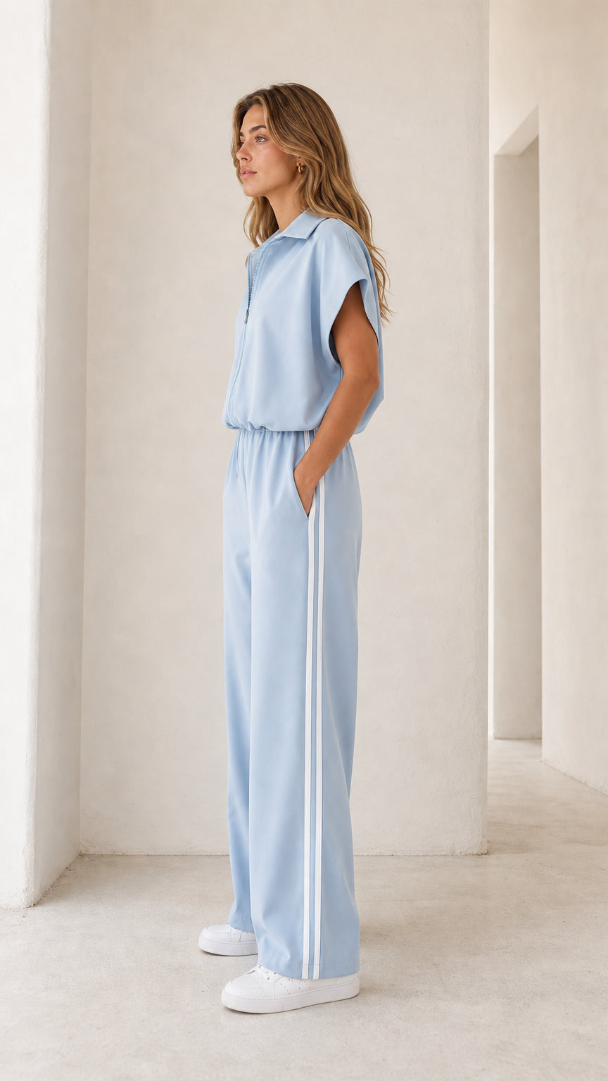 Side view of model wearing light blue zip-front wide leg jumpsuit showcasing white side stripes