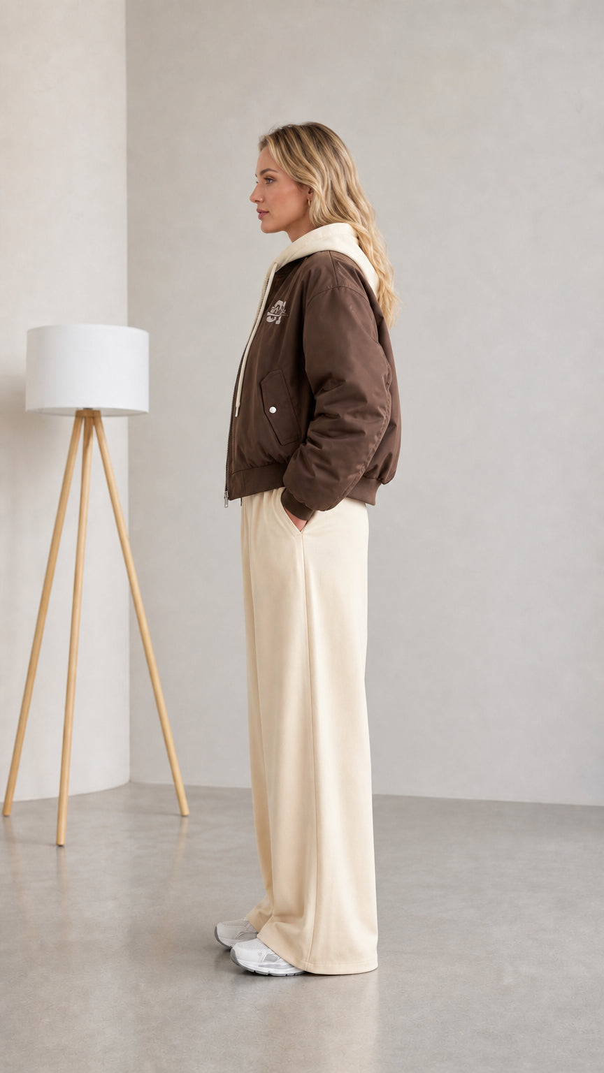 Side profile view of woman wearing brown hooded bomber jacket