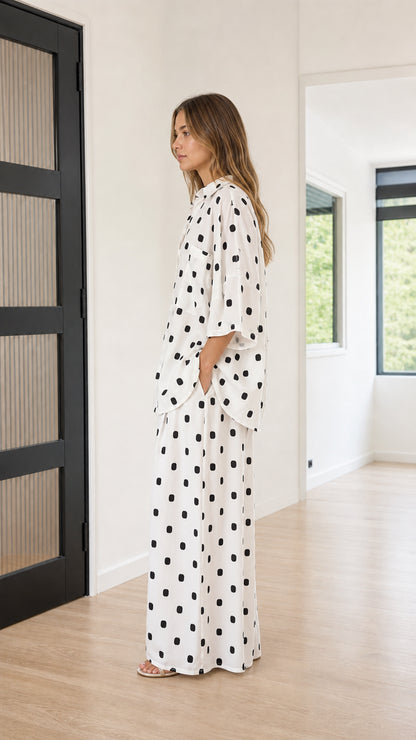 Side profile view of model wearing relaxed white polka dot matching two-piece set