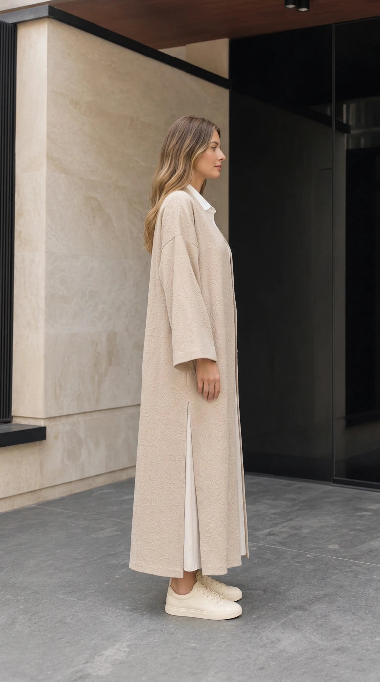 Side profile view of beige open front maxi duster coat showing side hem slit detail