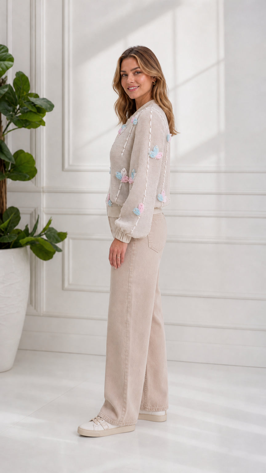 Side profile view of model wearing beige 3D floral knit bomber jacket