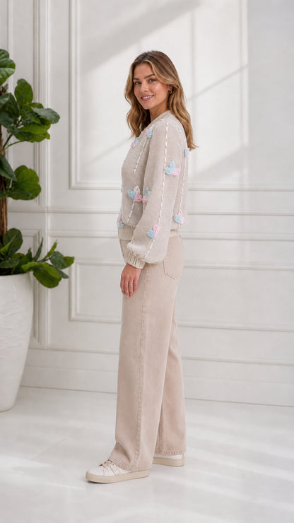 Side profile view of model wearing beige 3D floral knit bomber jacket