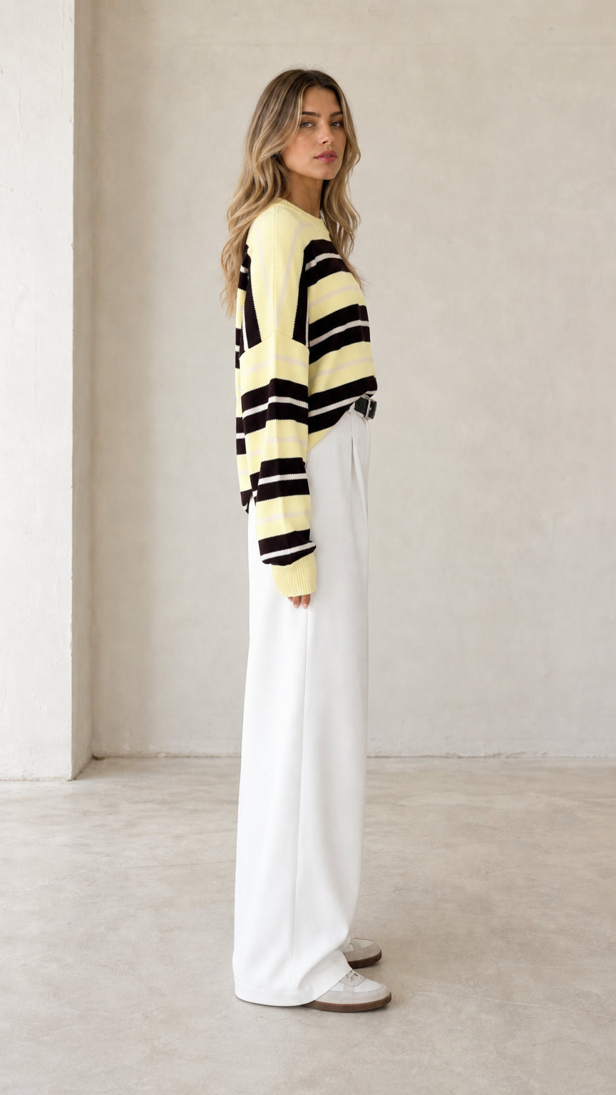 Side profile of woman wearing pale yellow striped long sleeve knit sweater