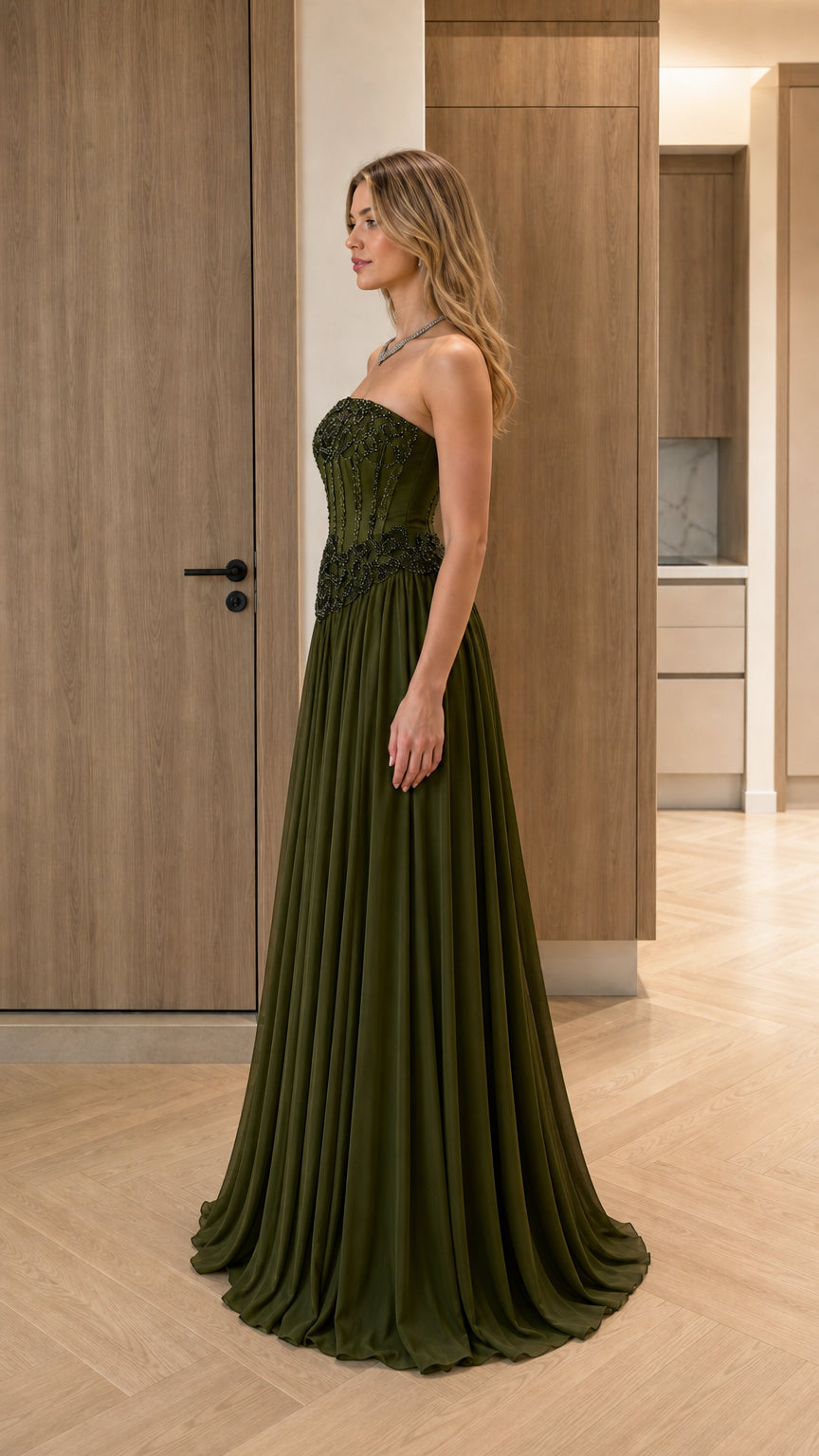 Side profile view of olive green strapless formal gown with pleated maxi skirt