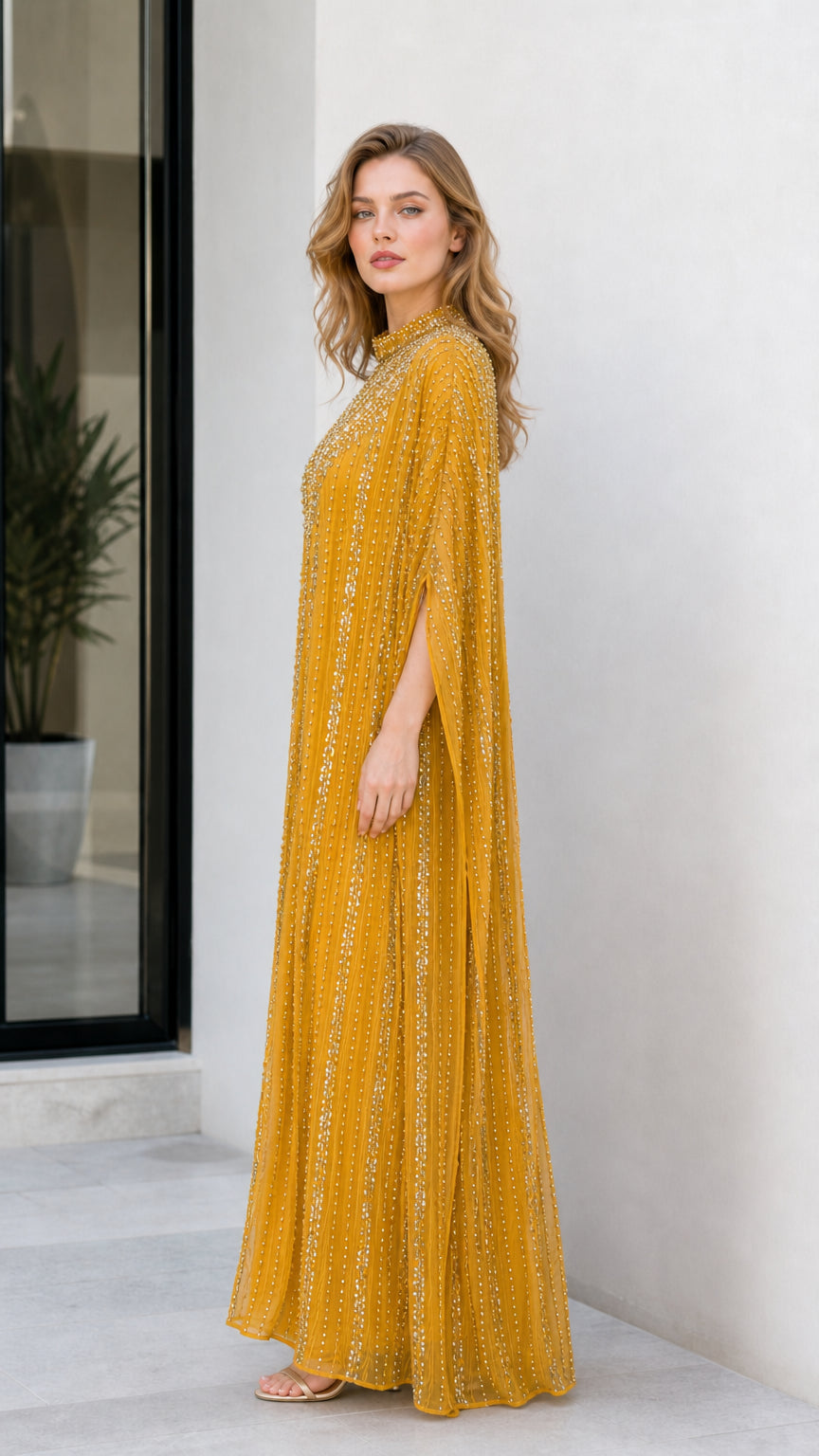 Side angle view of model in mustard yellow embellished kaftan dress