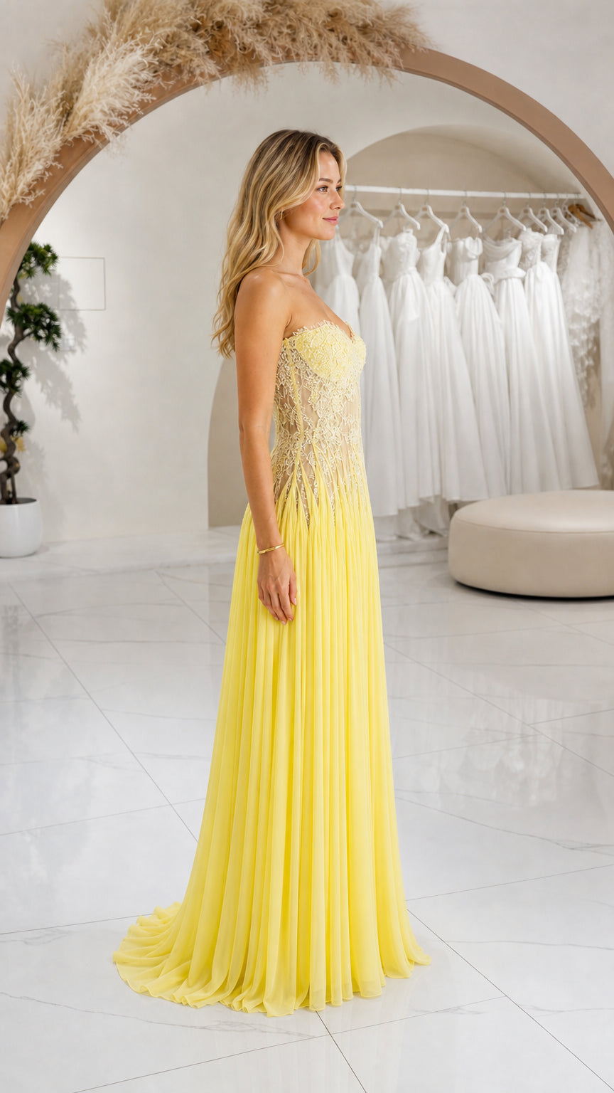 Side profile view of yellow strapless pleated chiffon maxi formal dress