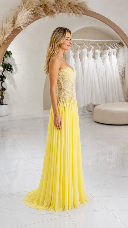 Side profile view of yellow strapless pleated chiffon maxi formal dress
