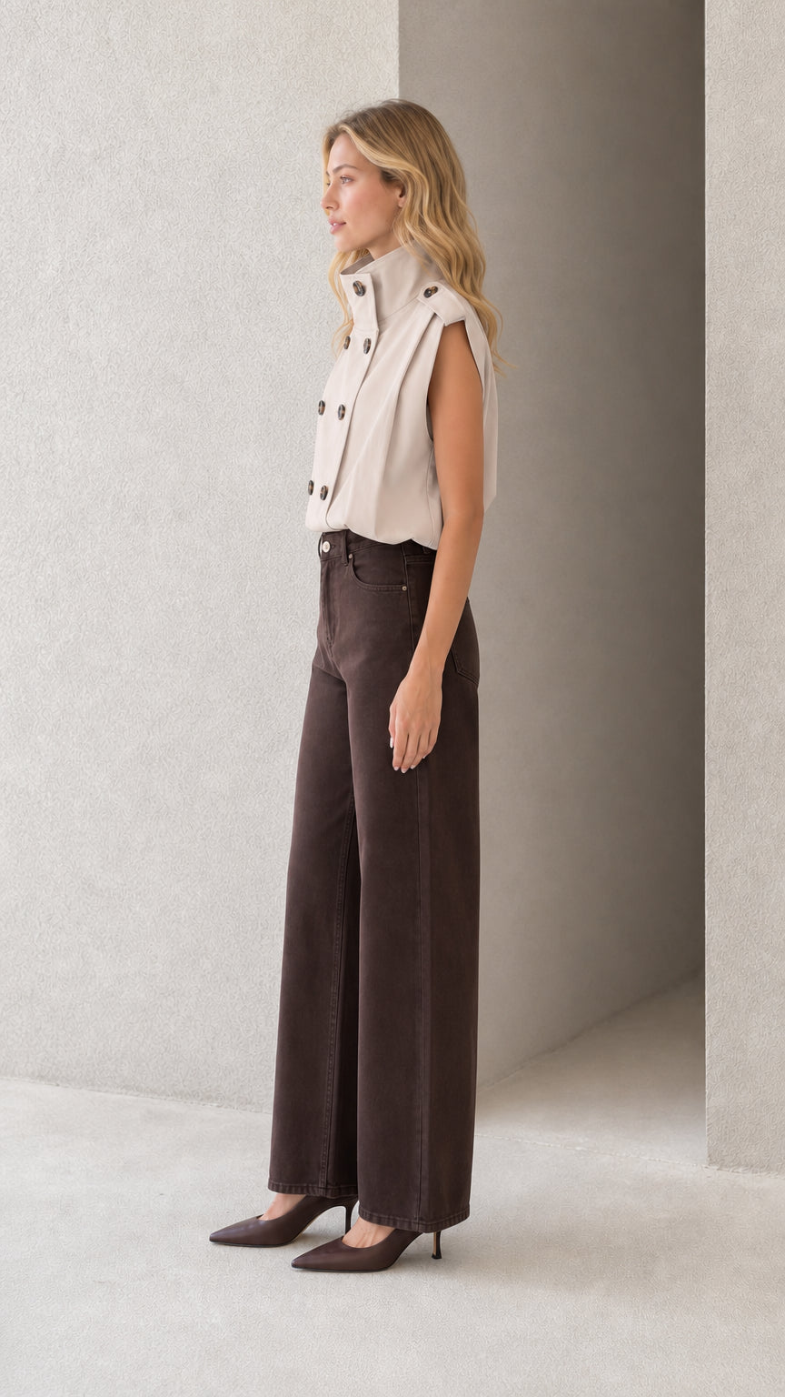 Side profile of model wearing beige sleeveless double-breasted high neck top