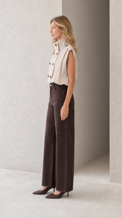 Side profile of model wearing beige sleeveless double-breasted high neck top