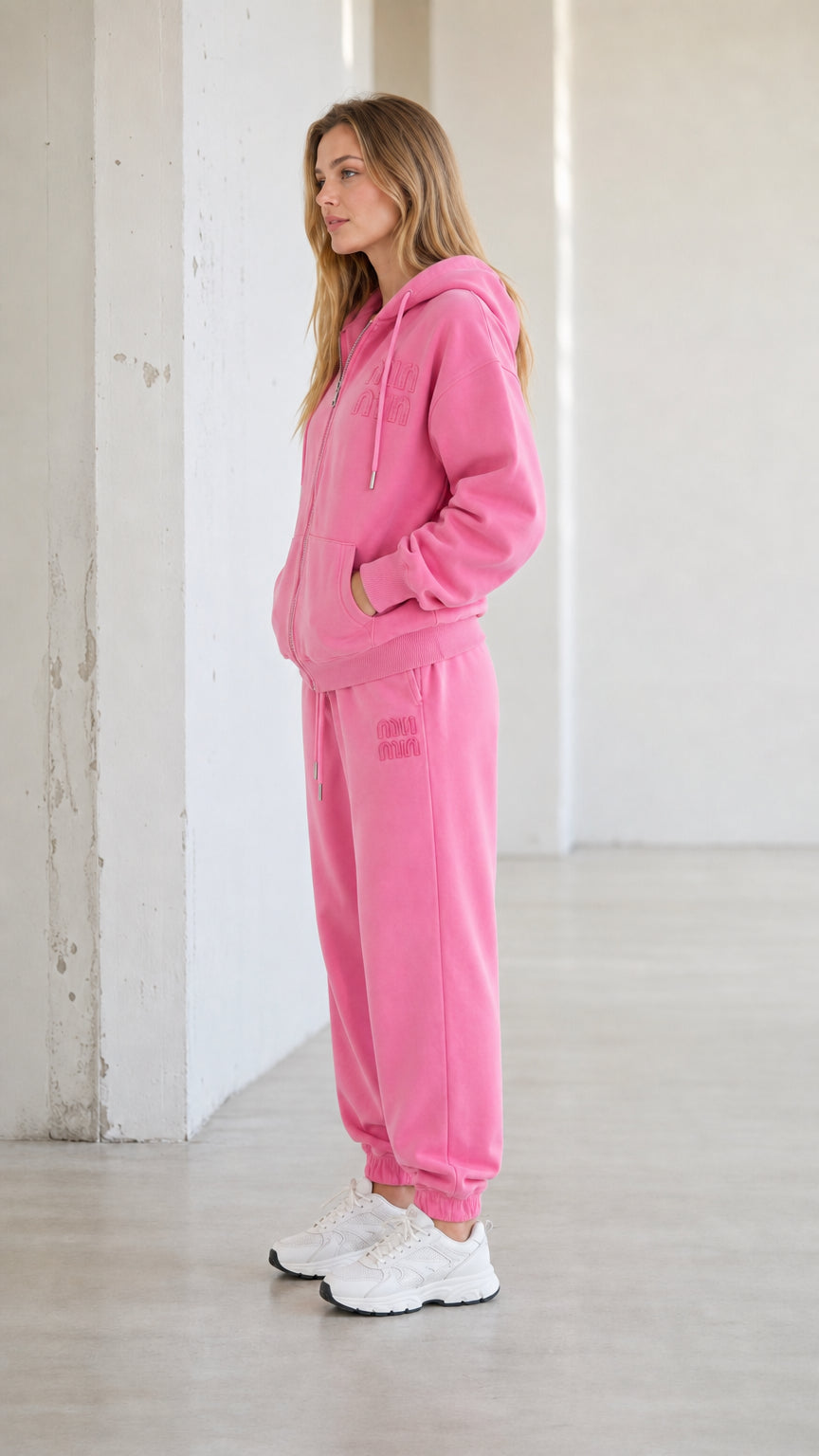 Side profile view of model wearing pink two-piece tracksuit set