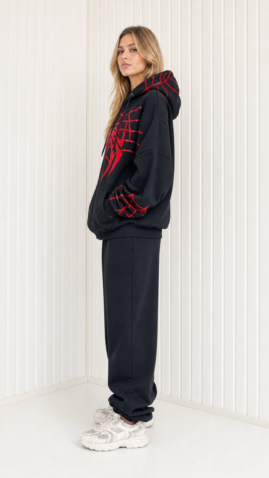 Side profile view of model in black graphic tracksuit set