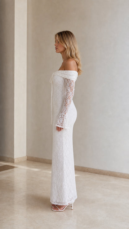 Side profile view of woman modeling white lace off-the-shoulder floor-length dress
