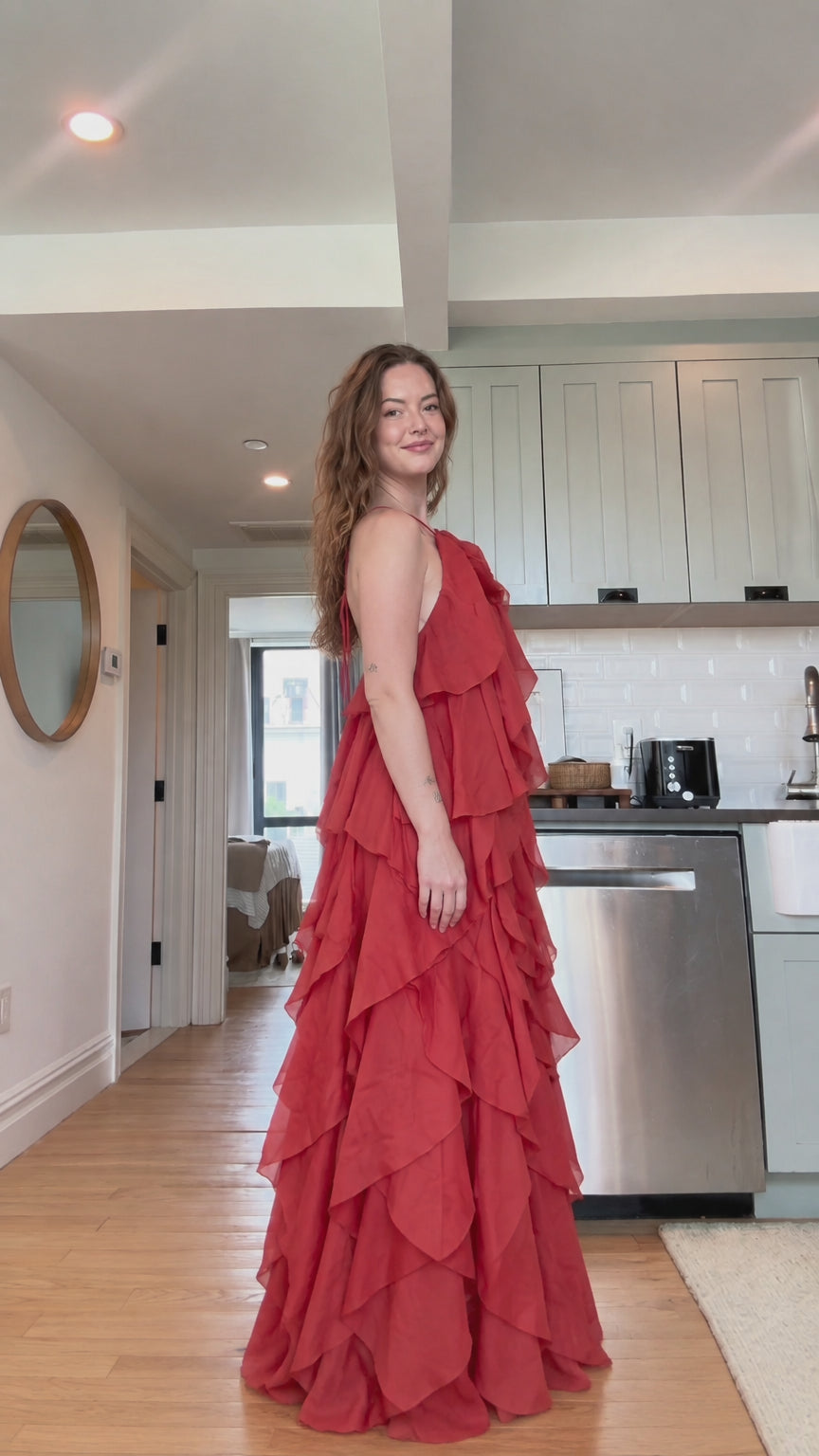 Side angle view of model posing in flowing rust red tiered maxi dress