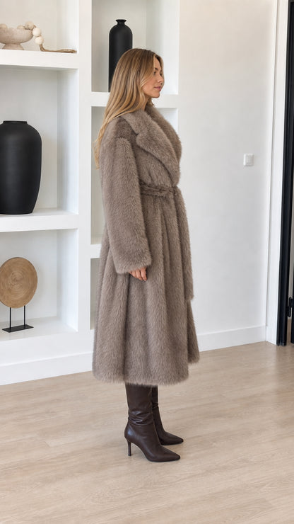 Side profile view of taupe longline faux fur coat showing relaxed drape and midi length