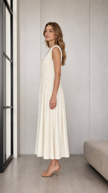 Side profile view of woman modeling Cream sleeveless pleated A-line midi dress