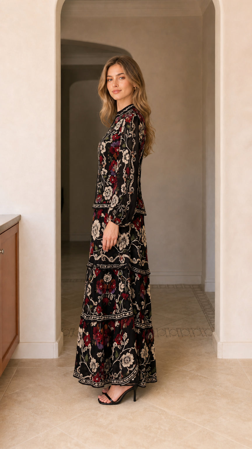 Side angle view of model wearing black long sleeve floral tiered maxi dress