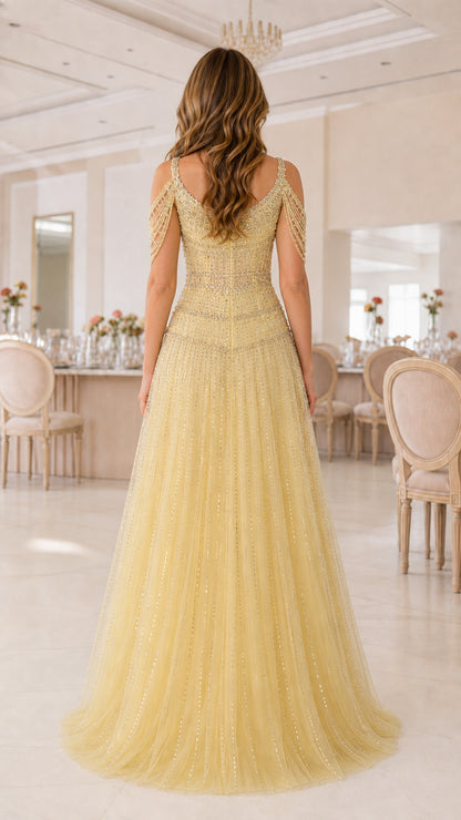 Back view of model showing beaded shoulder fringe and flowing yellow tulle skirt