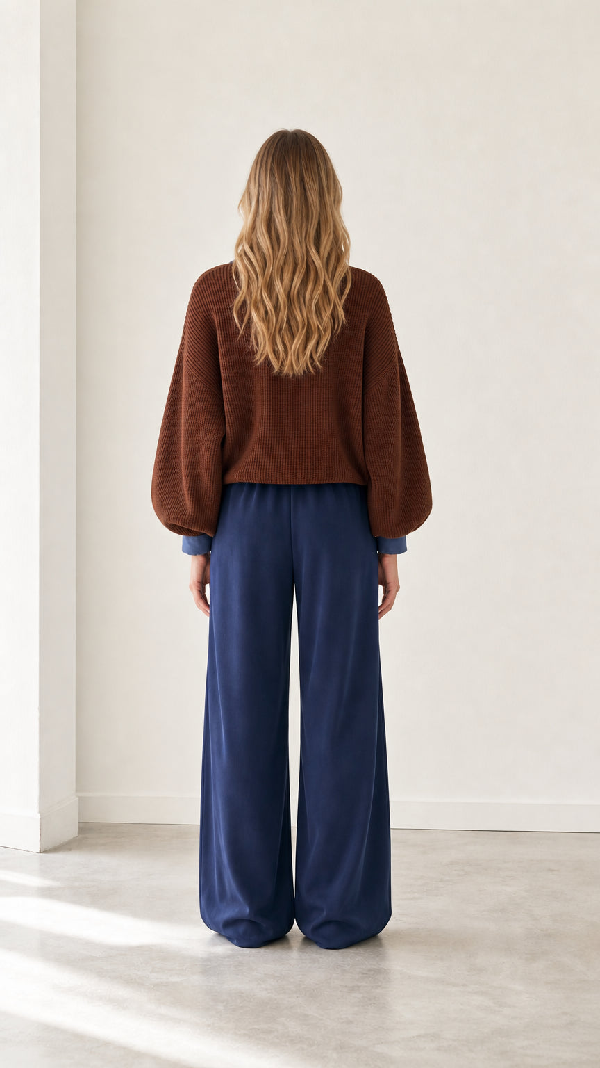 Back view of model wearing brown lantern sleeve ribbed knit sweater