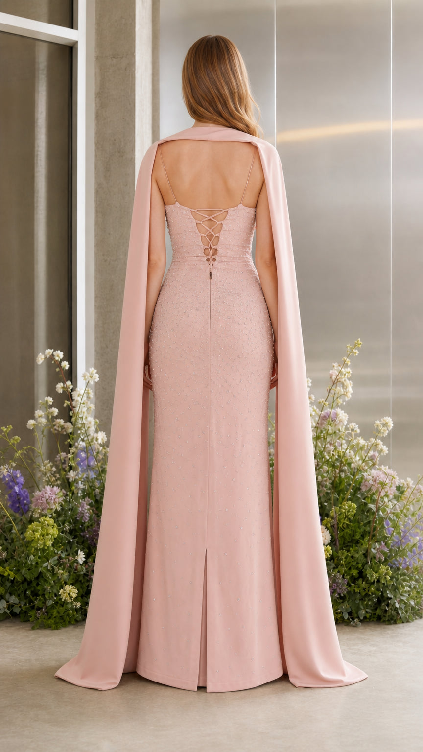 Back view of blush pink gown displaying corset lace-up back and flowing cape