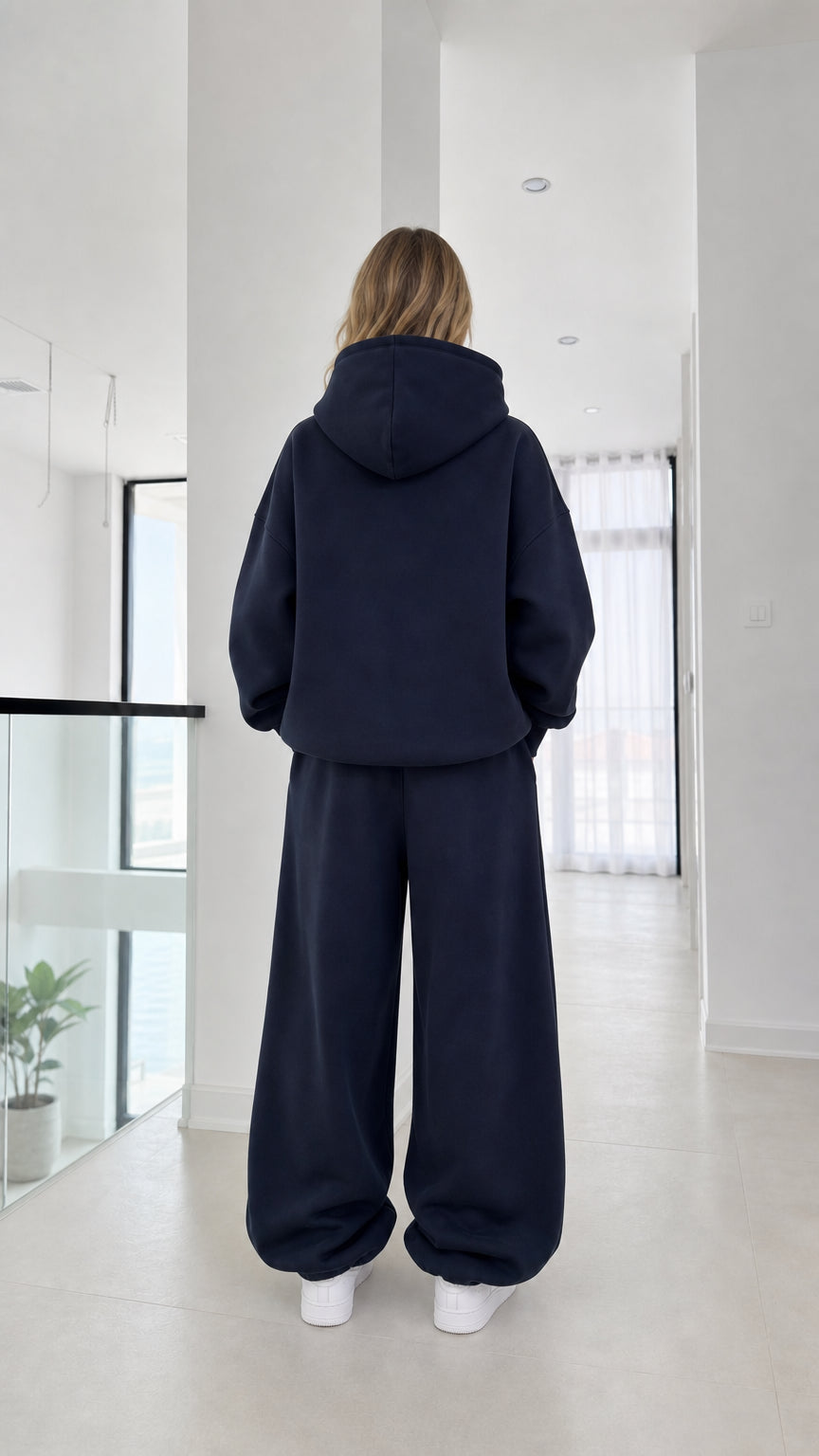 Back full-length view of model in the navy fleece hoodie and sweatpants