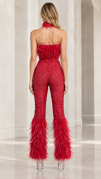 Back view of the red open-back sequin jumpsuit with halter neck and feather trims