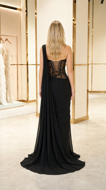 Back view of black corset evening gown featuring lace-up back and long draped train
