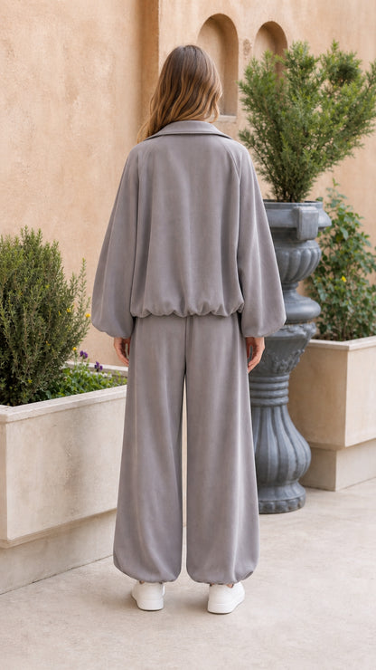 Back view of woman showing relaxed fit of grey zip jacket and wide balloon pants