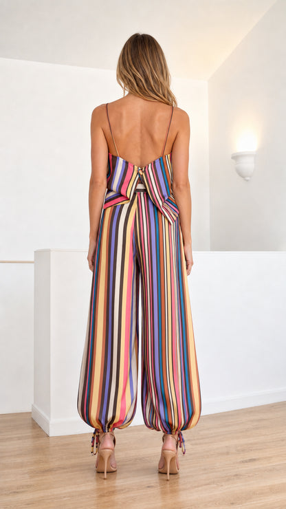 Back view of model in striped cami jumpsuit showing open back cutout detail and tied hems