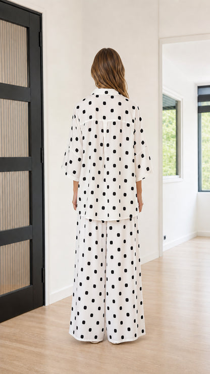 Back view of model wearing white polka dot button-down shirt and palazzo pants