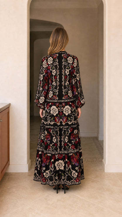 Back view of model showing tiered skirt and back bodice of black floral maxi dress