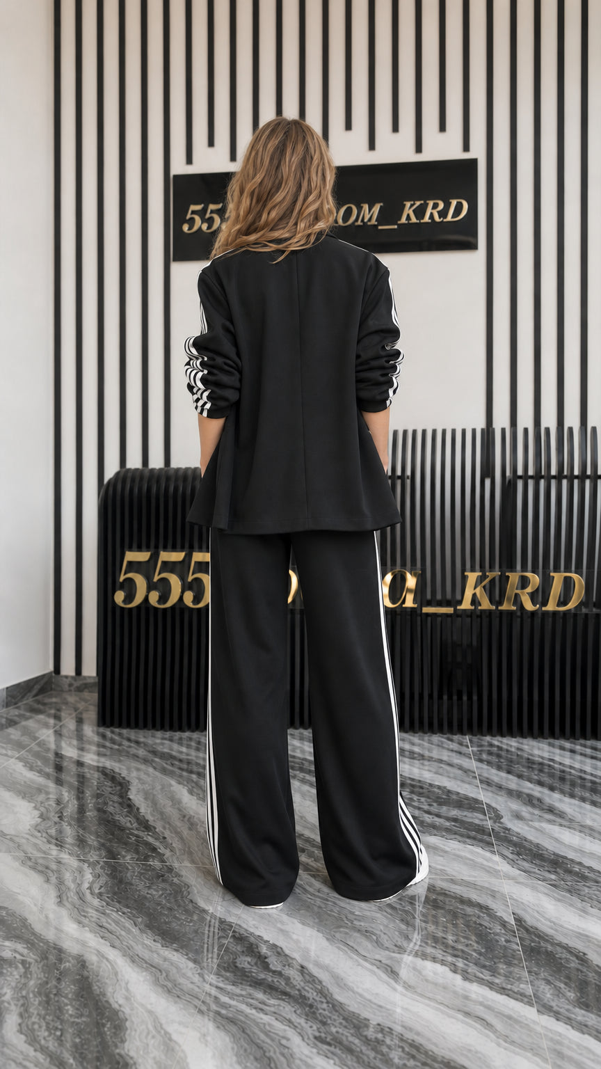 Back view of women's black relaxed blazer and wide-leg track pants